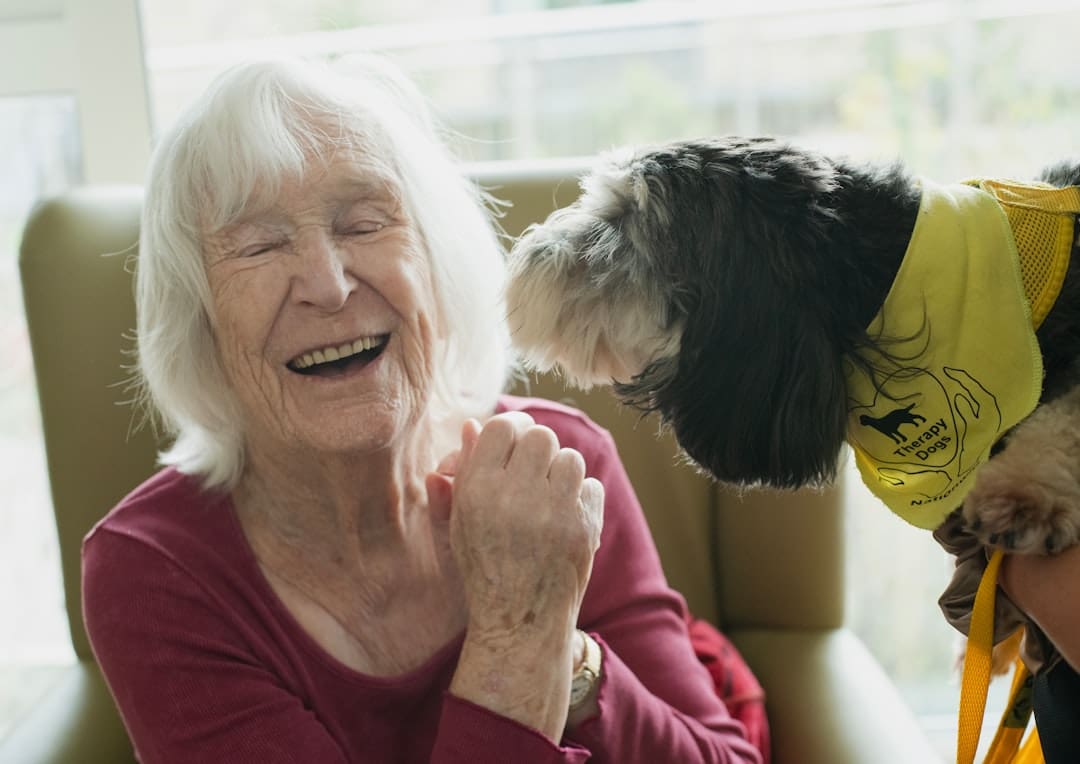 university therapy dog — Elderly woman laughing with a dog
